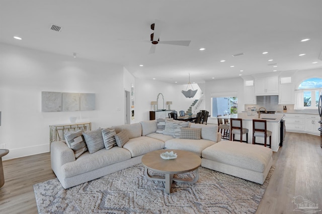 living room with light wood-type flooring, a ceiling fan, recessed lighting, healthy amount of natural light, and baseboards