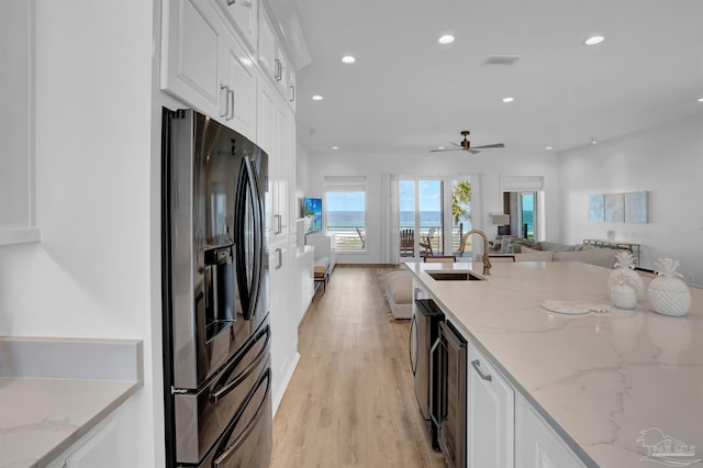 kitchen with black fridge, a sink, beverage cooler, open floor plan, and white cabinetry