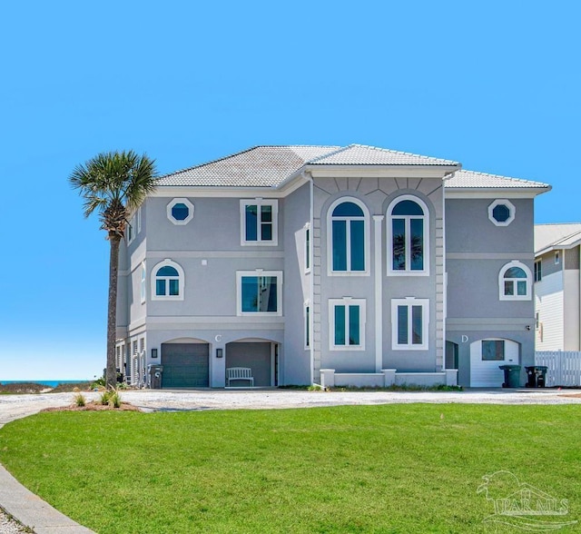 view of front facade with stucco siding, a front lawn, an attached garage, and a tiled roof
