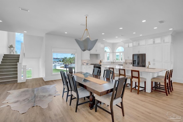 dining room with light wood-type flooring, recessed lighting, and stairs
