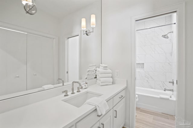 bathroom featuring toilet, vanity,  shower combination, and wood finished floors
