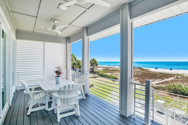 sunroom / solarium with ceiling fan, view of water and beach, and hardwood / wood-style floors