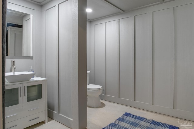half bath with toilet, vanity, and a decorative wall