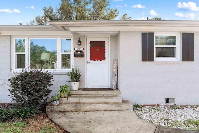view of exterior entry featuring brick siding and crawl space