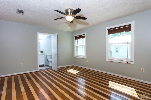 spare room with a textured ceiling, baseboards, a ceiling fan, and visible vents
