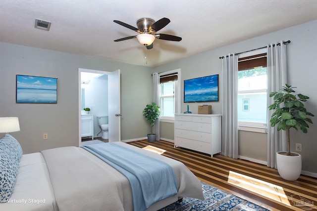 bedroom with visible vents, baseboards, multiple windows, and connected bathroom