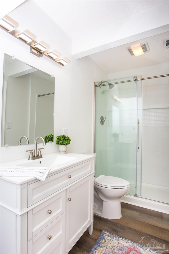 full bathroom with vanity, a stall shower, toilet, visible vents, and wood finished floors