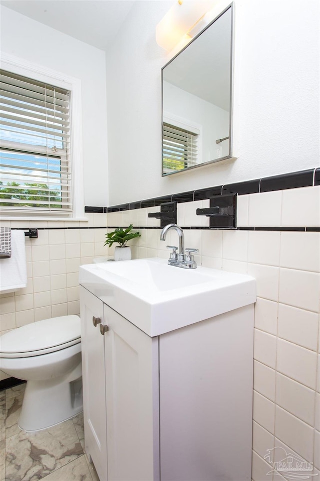 bathroom featuring vanity, tile walls, a wainscoted wall, and toilet