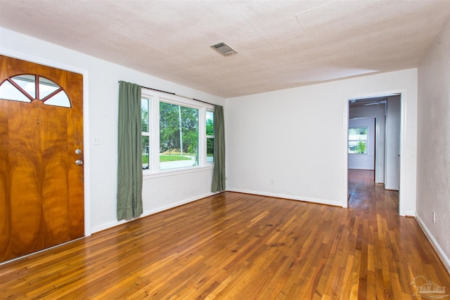 foyer with visible vents, hardwood / wood-style flooring, and baseboards