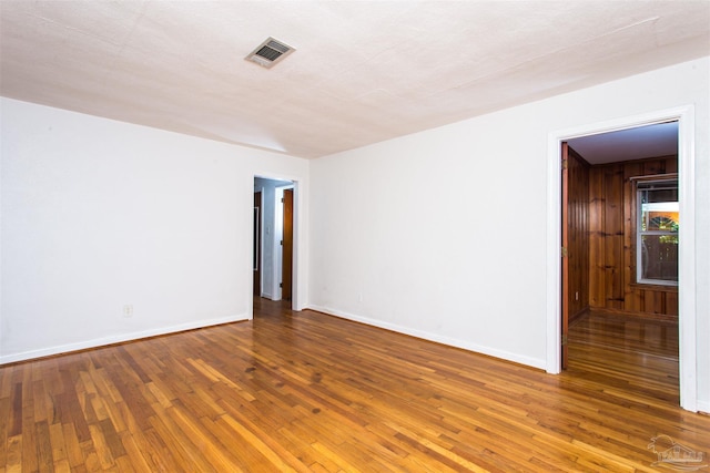 empty room with wood finished floors, baseboards, and visible vents