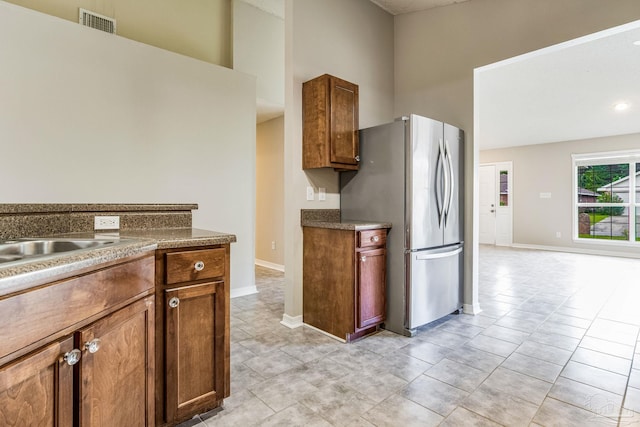 kitchen with light tile patterned flooring, a towering ceiling, and stainless steel fridge