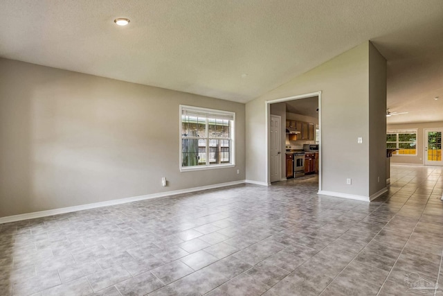 unfurnished room featuring ceiling fan, lofted ceiling, a textured ceiling, and a wealth of natural light