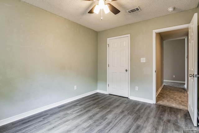 unfurnished bedroom featuring ceiling fan, dark wood-type flooring, and a textured ceiling