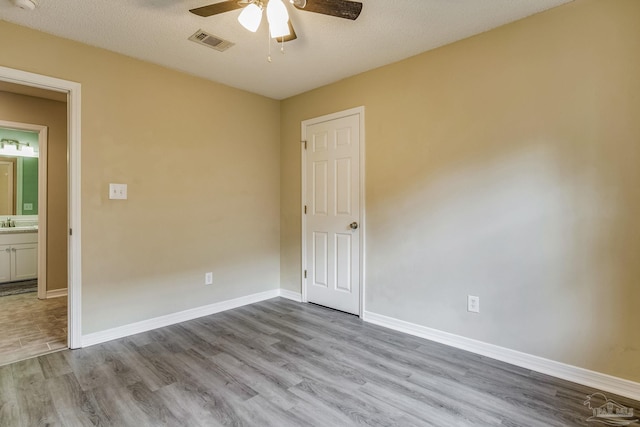 spare room featuring a textured ceiling, ceiling fan, and light hardwood / wood-style flooring