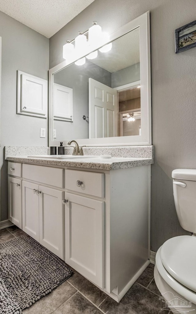 bathroom with vanity, tile patterned flooring, toilet, and a textured ceiling