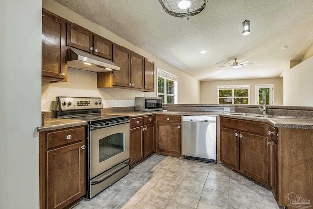 kitchen featuring decorative light fixtures, a wealth of natural light, stainless steel appliances, and kitchen peninsula