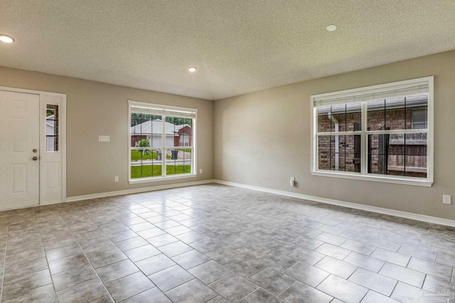 unfurnished room with light tile patterned flooring and a textured ceiling