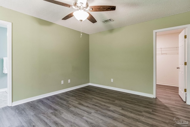 spare room featuring dark hardwood / wood-style flooring, ceiling fan, and a textured ceiling