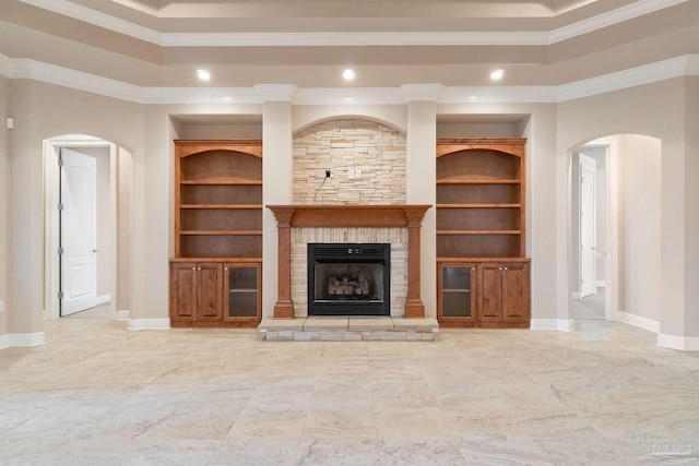 unfurnished living room featuring built in shelves, a tray ceiling, a fireplace, and baseboards