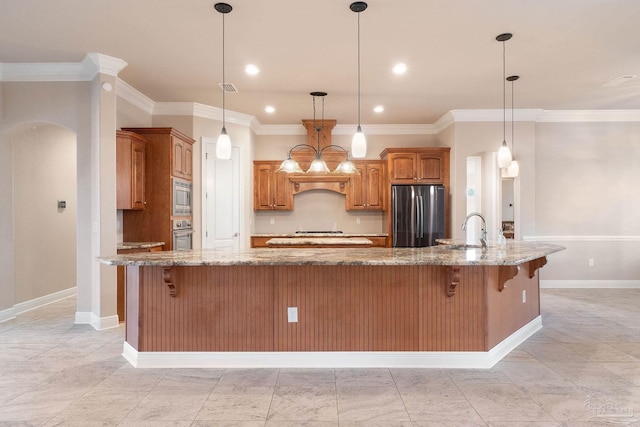 kitchen with appliances with stainless steel finishes, arched walkways, a sink, and a breakfast bar