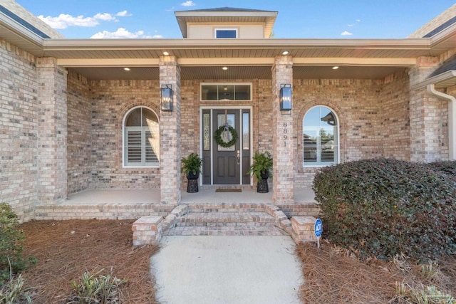 property entrance with covered porch and brick siding