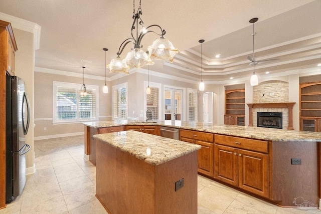 kitchen with a spacious island, appliances with stainless steel finishes, a stone fireplace, and ornamental molding