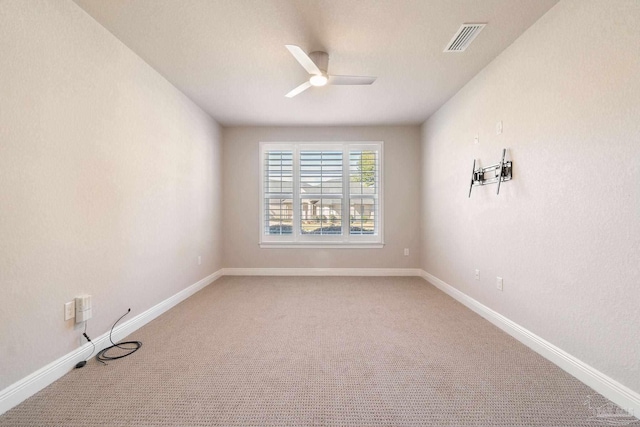 empty room with a ceiling fan, visible vents, light carpet, and baseboards