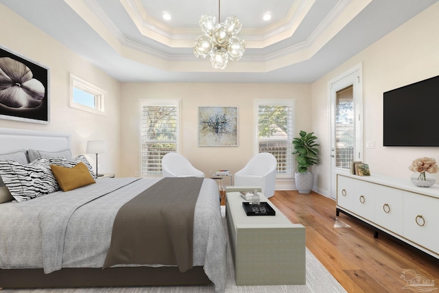 bedroom featuring light wood-style flooring, multiple windows, a tray ceiling, and crown molding