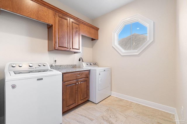 laundry room with cabinet space, washing machine and dryer, and baseboards