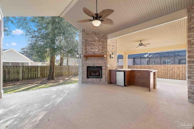 view of patio / terrace with an outdoor brick fireplace, fence, and a ceiling fan