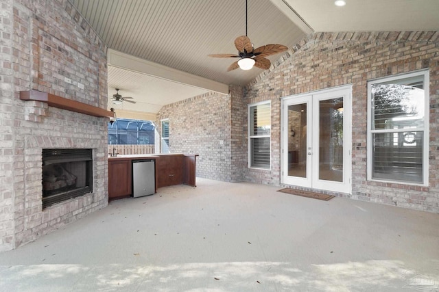 view of patio featuring an outdoor brick fireplace, french doors, and a ceiling fan