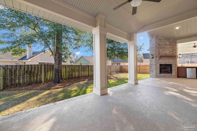 view of patio / terrace featuring ceiling fan, an outdoor brick fireplace, and a fenced backyard