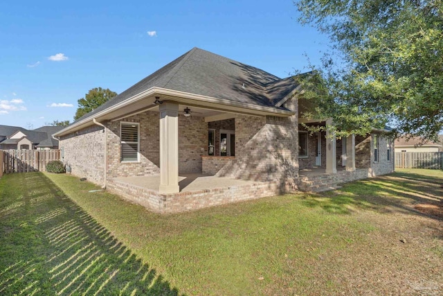 back of property featuring a lawn, ceiling fan, a fenced backyard, a patio area, and brick siding