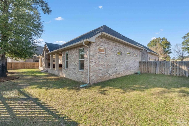 view of home's exterior with brick siding, a lawn, and a fenced backyard