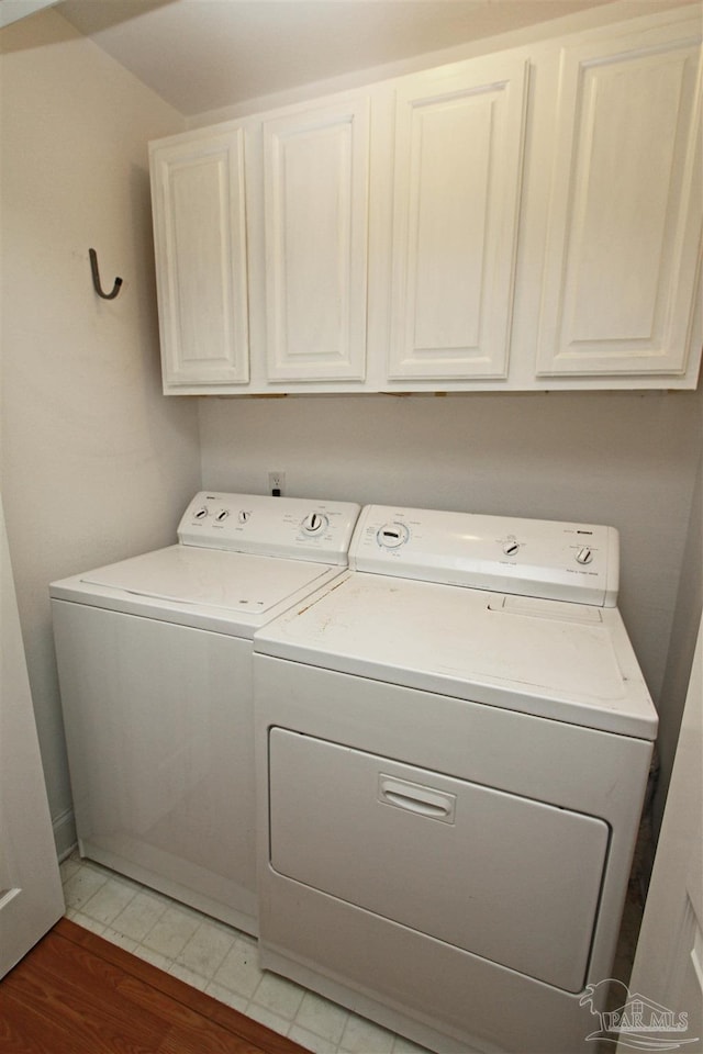 clothes washing area with independent washer and dryer, light hardwood / wood-style flooring, and cabinets