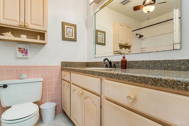 bathroom with vanity, a shower, tile patterned floors, tile walls, and toilet