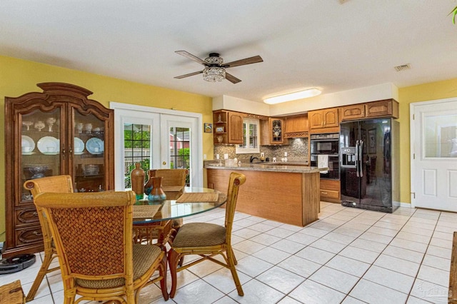 kitchen with kitchen peninsula, decorative backsplash, black appliances, light tile patterned floors, and french doors