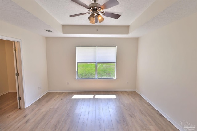 2608 Salamanca St, Navarre, FL 32566 - spare room featuring a tray ceiling, a textured ceiling, light wood-style floors, baseboards, and ceiling fan
