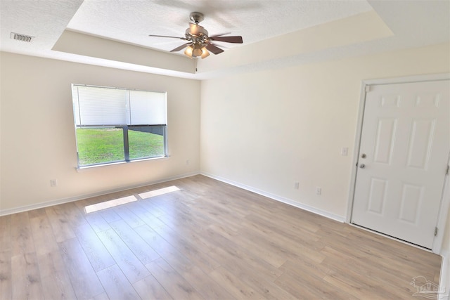 2608 Salamanca St, Navarre, FL 32566 - empty room with a tray ceiling, a ceiling fan, baseboards, light wood-type flooring, and a textured ceiling