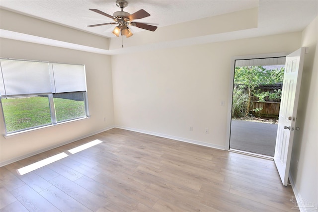 2608 Salamanca St, Navarre, FL 32566 - empty room featuring light wood-style flooring, a tray ceiling, ceiling fan, and baseboards