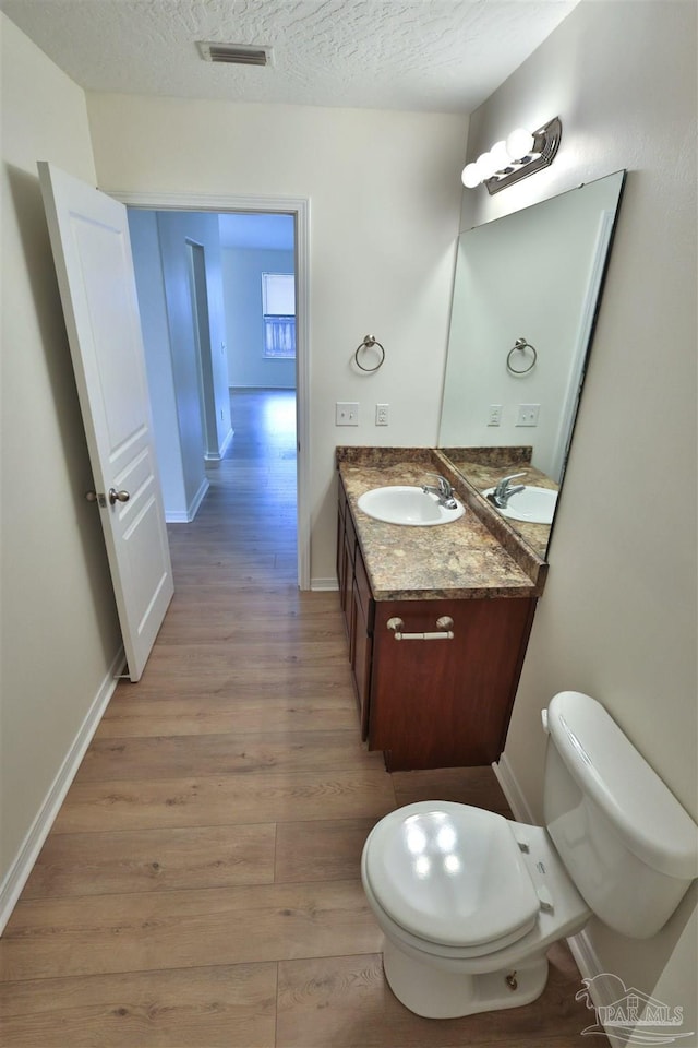 2608 Salamanca St, Navarre, FL 32566 - bathroom with wood finished floors, vanity, toilet, baseboards, and a textured ceiling