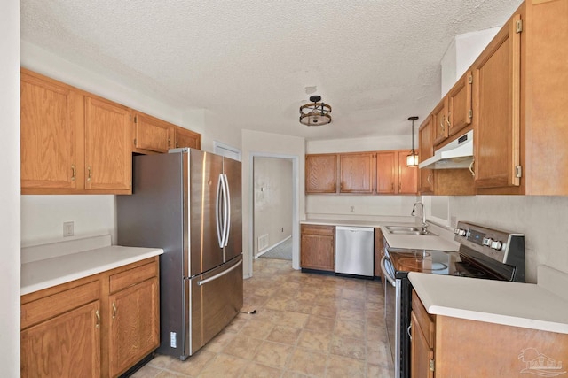 kitchen featuring sink, a textured ceiling, hanging light fixtures, and appliances with stainless steel finishes