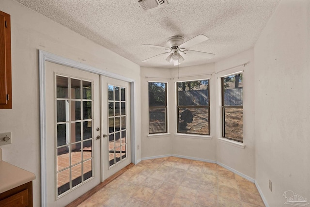 unfurnished sunroom featuring plenty of natural light, ceiling fan, and french doors