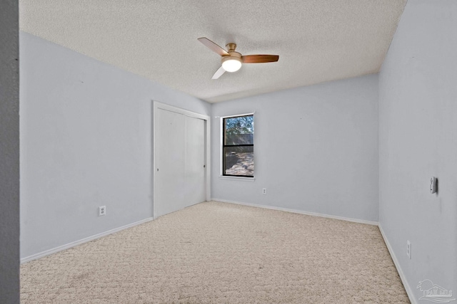 carpeted spare room with a textured ceiling and ceiling fan