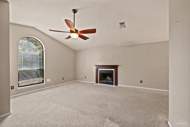 unfurnished living room featuring light carpet, vaulted ceiling, ceiling fan, a tiled fireplace, and a textured ceiling