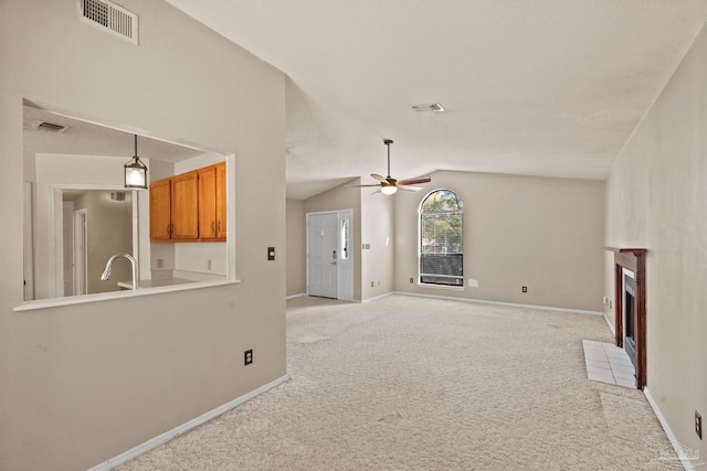 unfurnished living room with ceiling fan, sink, light carpet, and vaulted ceiling