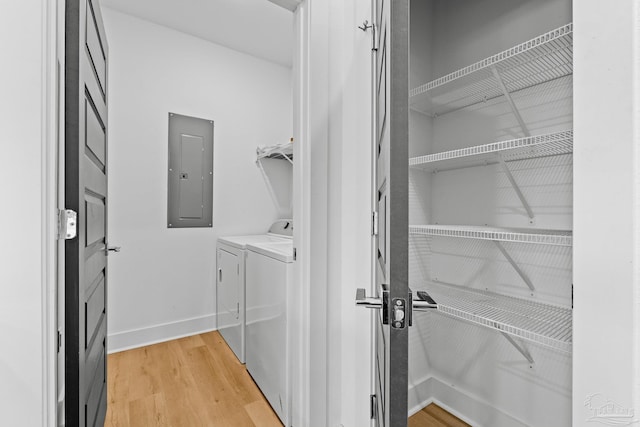 clothes washing area with hardwood / wood-style flooring, electric panel, and washing machine and dryer