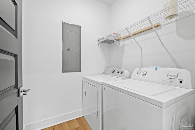 washroom with separate washer and dryer, electric panel, and light wood-type flooring