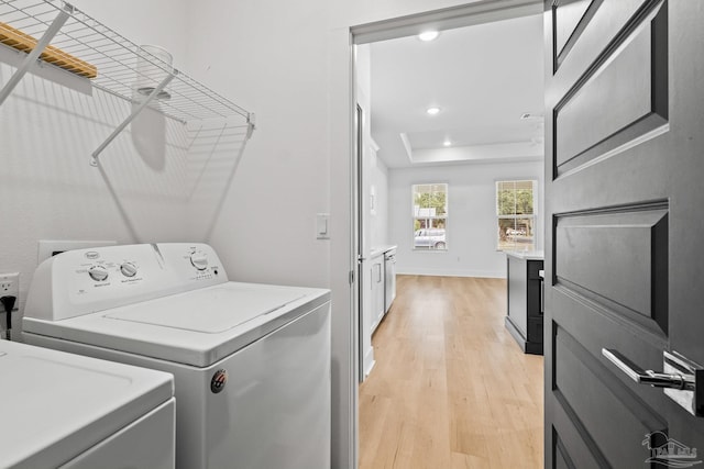 laundry area with washer and clothes dryer and light hardwood / wood-style floors