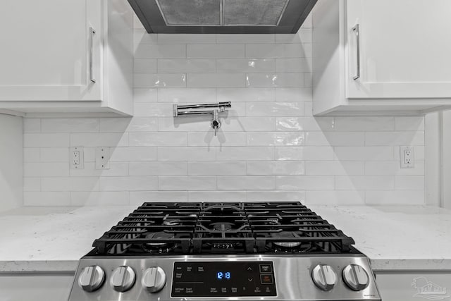 details featuring exhaust hood, light stone countertops, gas stove, and white cabinets